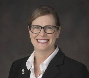 Councillor Skipsey is pictured in front of a dark grey background. She wears dark-rimmed glasses, a black suit jacket, and a white shirt. There is a brooch on her left lapel.