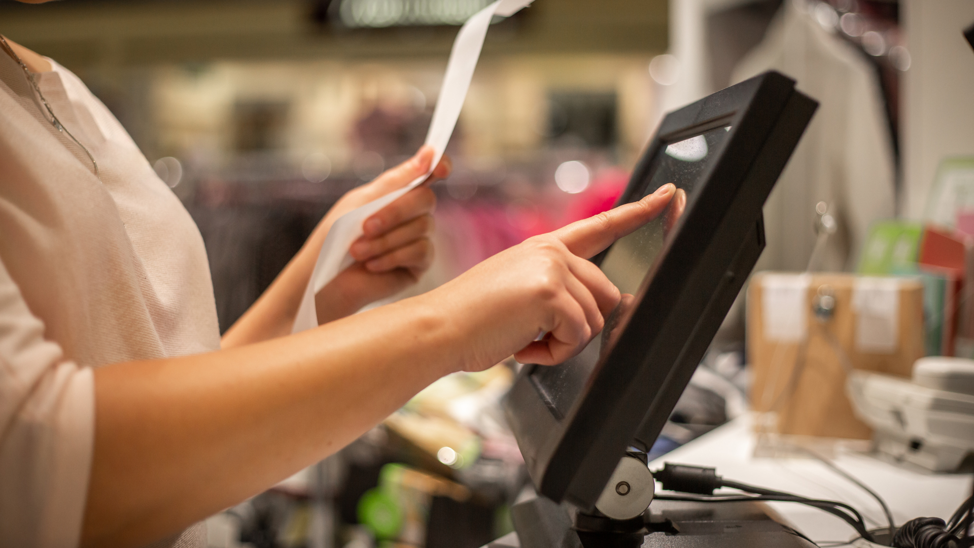 A person holds a receipt paper while inputting information into a computer using the touchscreen. Licences are required to operate a business in Qualicum Beach.