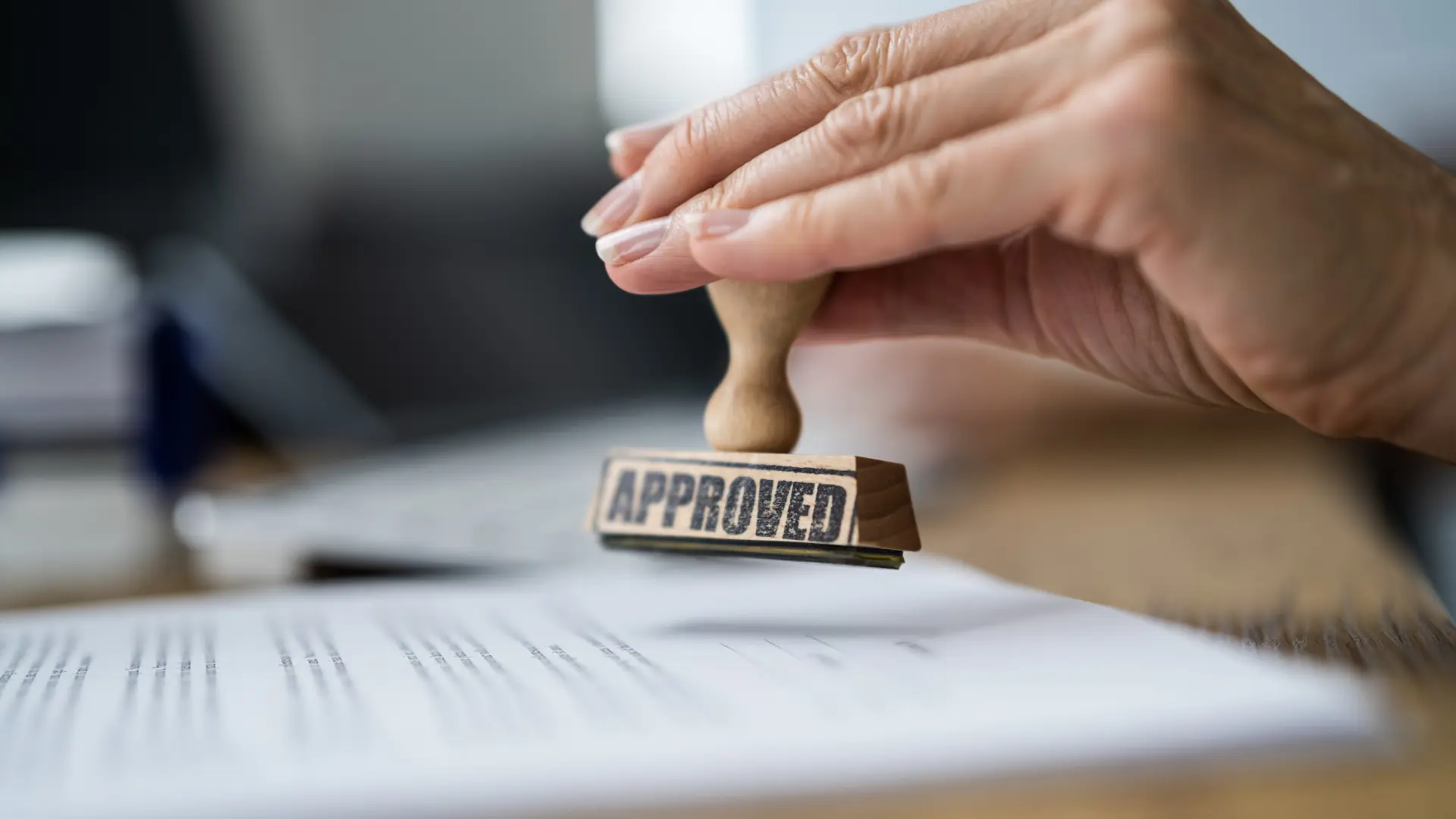 Person putting a stamp of approval on a document.